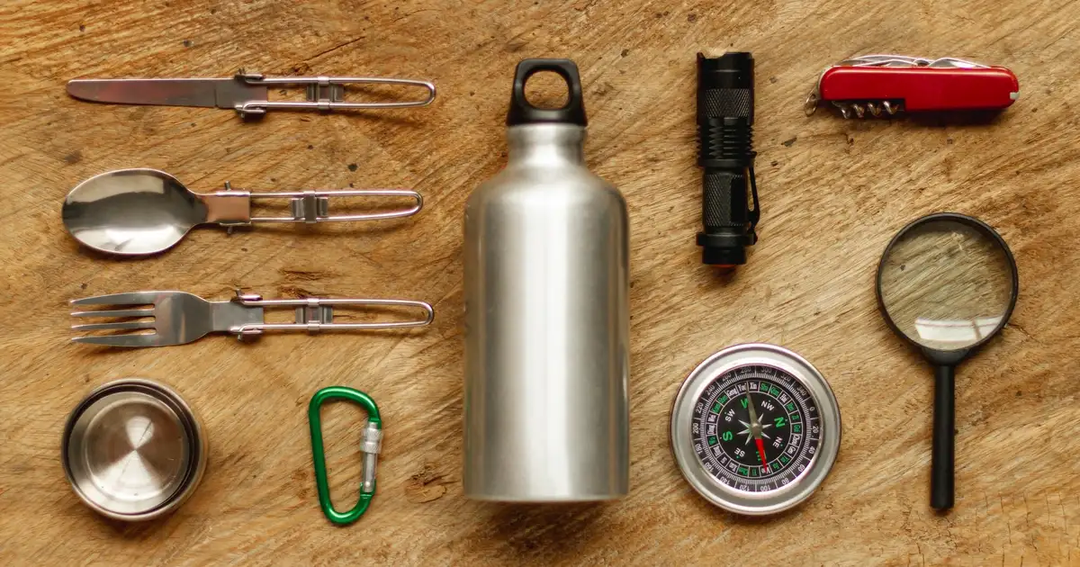 Kit de emergencia compacto para una persona organizado sobre una estantería en un piso pequeño: agua, linterna, botiquín y conservas