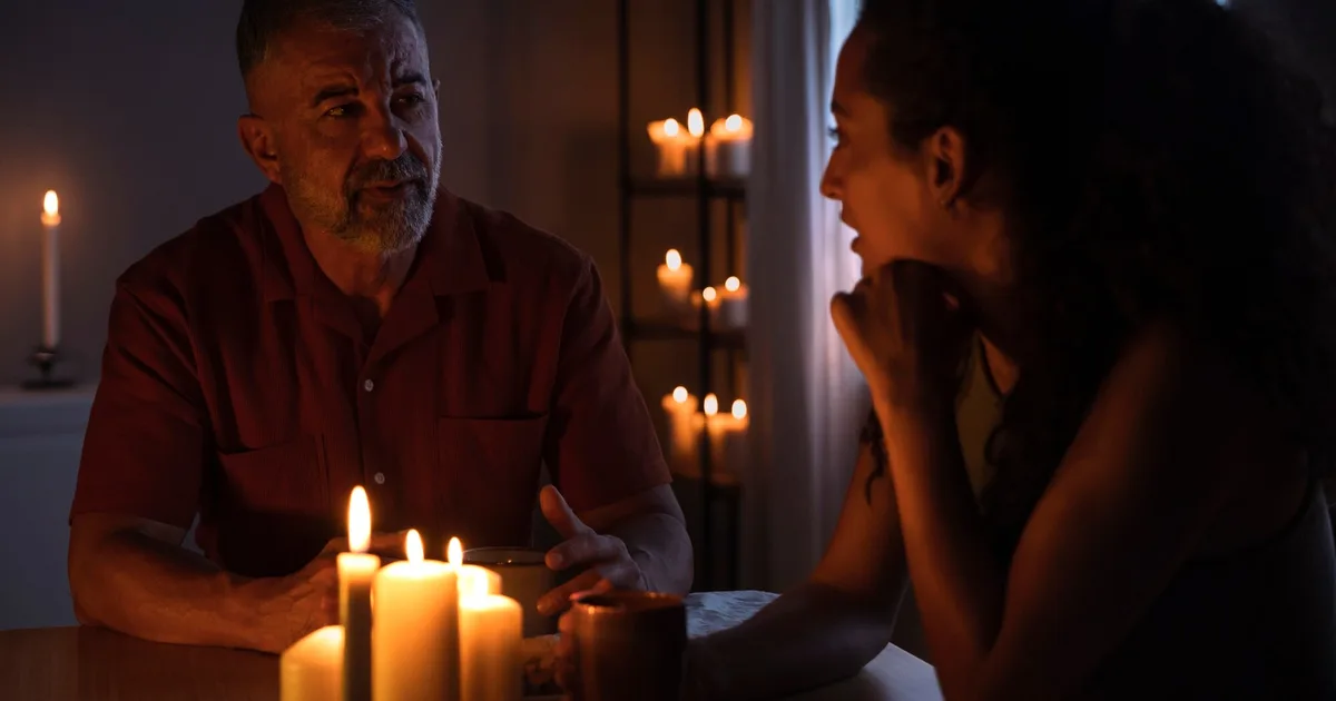 Dos personas conversando a la luz de las velas durante un apagón prolongado en casa