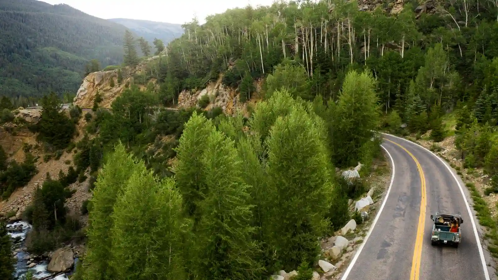 Paso fronterizo terrestre entre España y Francia en los Pirineos con coche familiar cargado, atlas europeo y pasaportes preparados para evacuación internacional