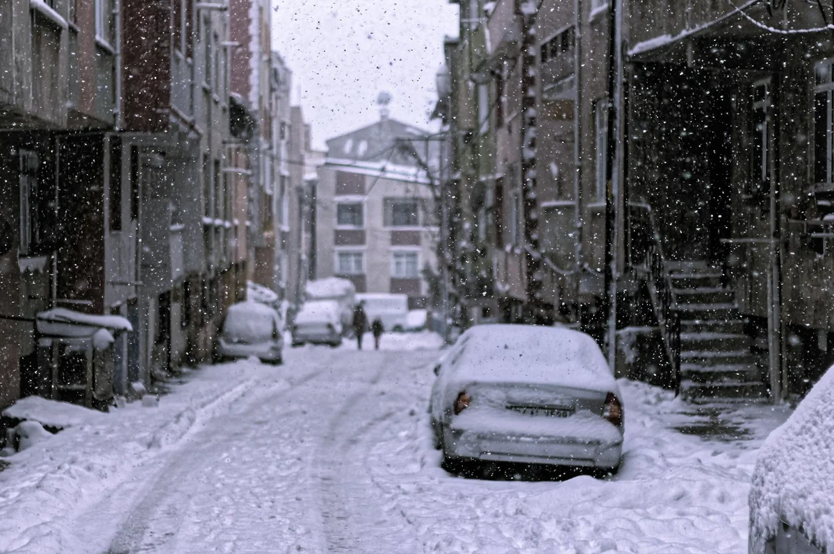 Calle nevada con coches durante una nevada extrema