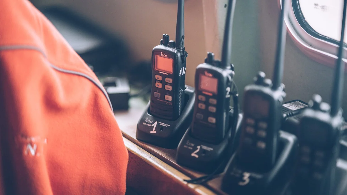 Cuatro walkie-talkies cargando en estaciones sobre superficie de madera — kit familiar de comunicación lista para emergencia
