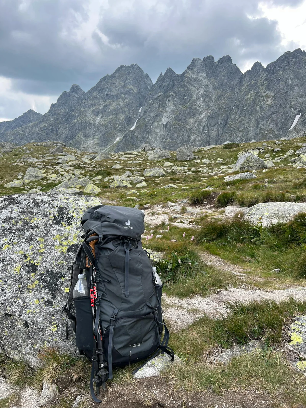 Mochila de montaña en terreno rocoso con cumbres al fondo — equipo de supervivencia para Pirineos y alta montaña española